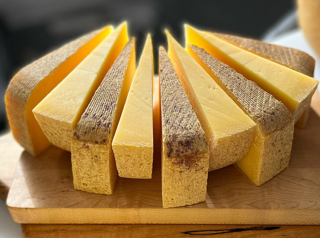 Slices of sharp, aged Iowa Alpine (a Gruyere style cheese) served on a cheeseboard with crackers and jam.