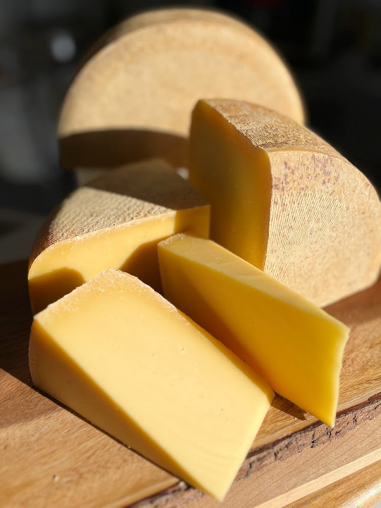 A wedge of Iowa Alpine, a farmstead alpine style cheese, showing its firm, semi-hard texture and natural rind.