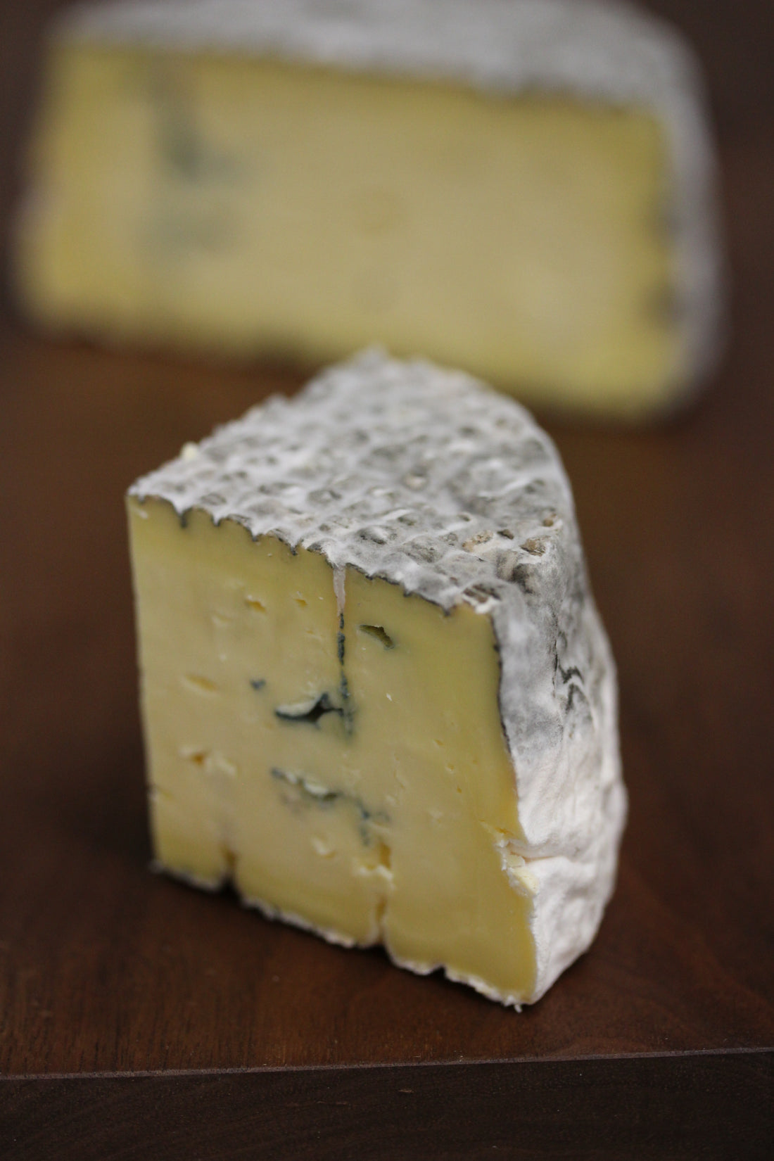 A quarter-wheel wedge of Lost Lake Blue, a creamy farmstead blue cheese, showing its rich blue veining and soft texture.