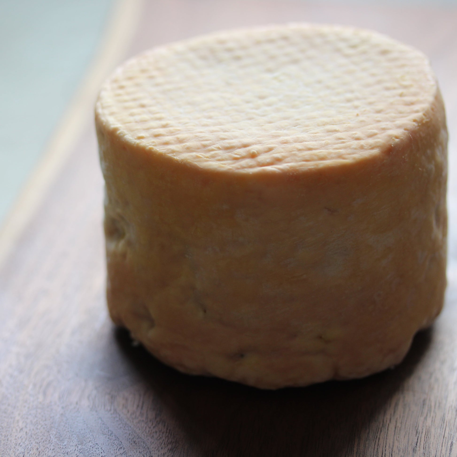 Round block of cheese on a wooden board