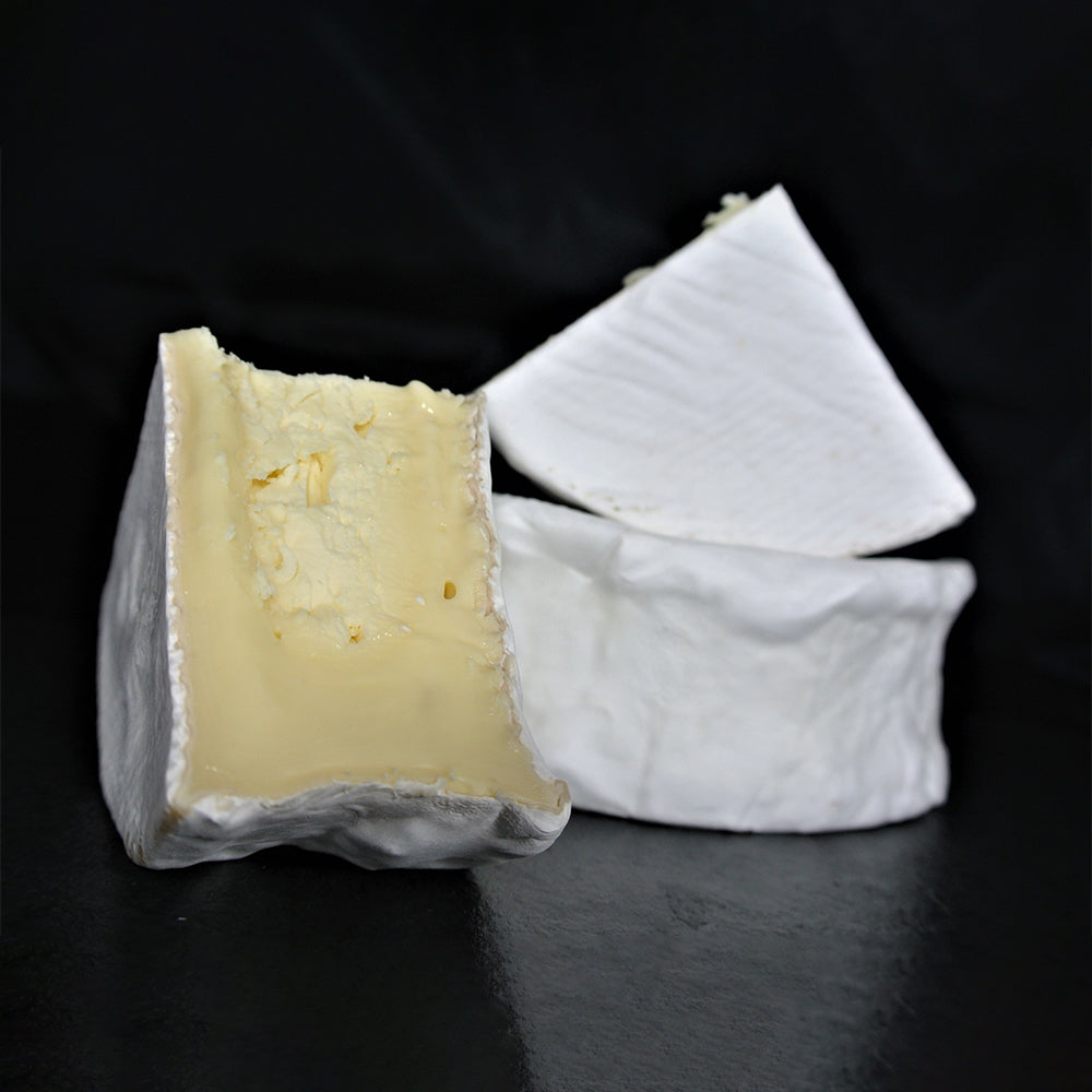 A quarter wheel of farmstead Camembert cheese from Lost Lake Farm, showing its white, bloomy rind and packaging.