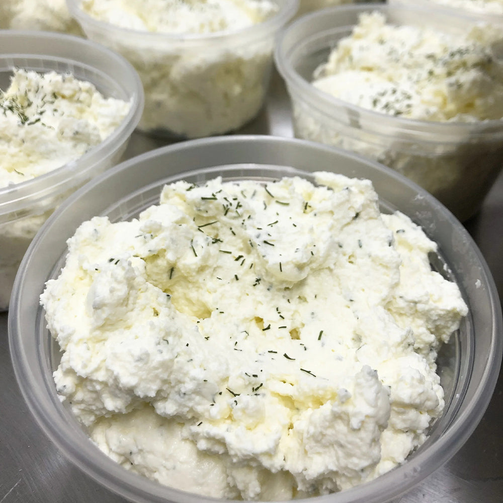 A container of plain farmstead quark cheese from Lost Lake Farm, with a spoon showing its smooth, creamy texture.