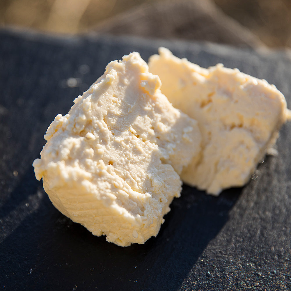 A close-up shot showing the firm yet creamy texture of Farmstead Feta, ready to be added to a salad.