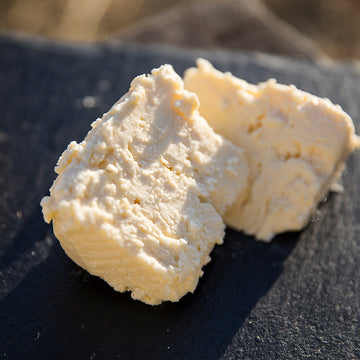 A close-up shot showing the firm yet creamy texture of Farmstead Feta, ready to be added to a salad.